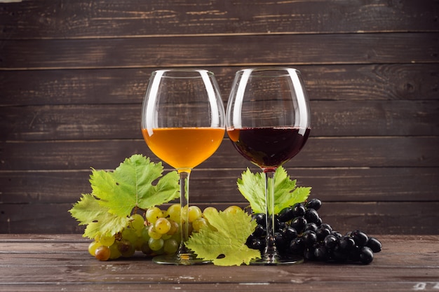 Copa de vino y racimo de uvas en mesa de madera