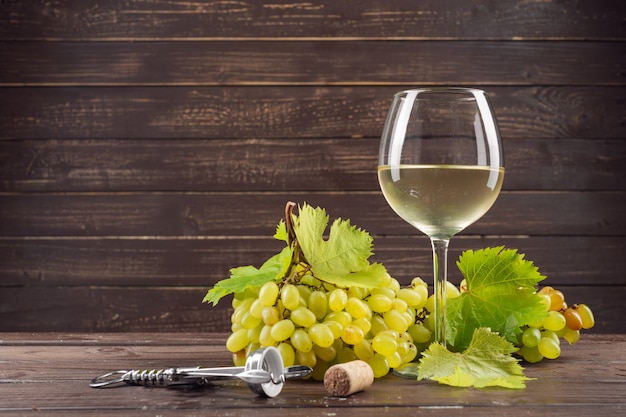 Copa de vino y racimo de uvas en mesa de madera