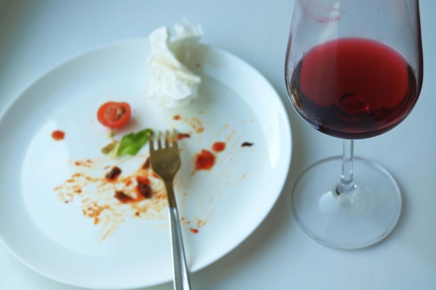 Copa de vino y sobras de comida en un plato blanco desenfocado