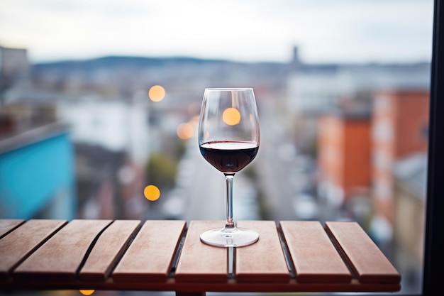 Una copa de vino tinto en un balcón con vistas a la ciudad