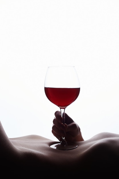 Copa de vino tinto en cuerpo femenino desnudo