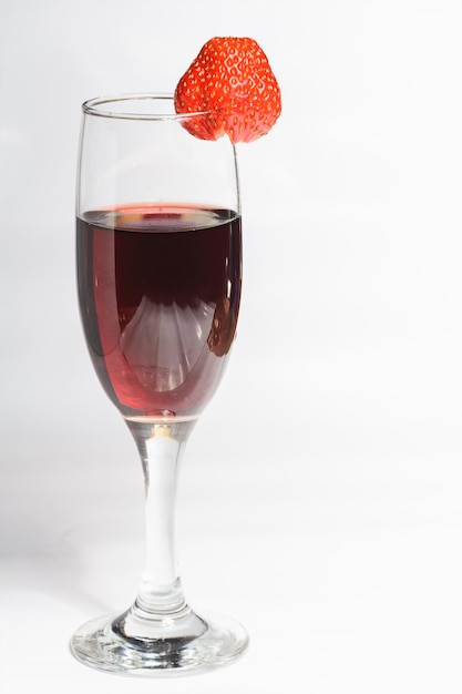 Una copa de vino tinto con fresas sobre un fondo blanco.