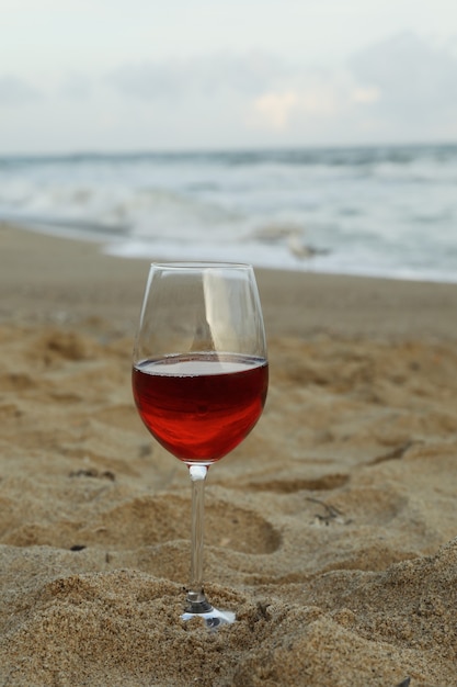 Copa de vino tinto en la playa de arena