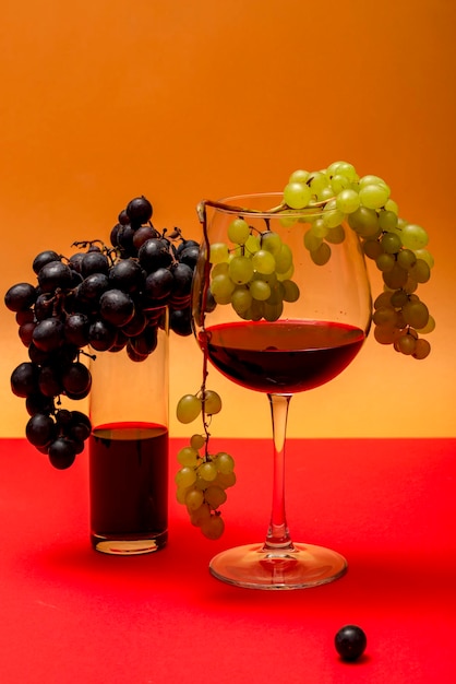 Una copa de vino tinto y un racimo de uvas sobre un fondo de color