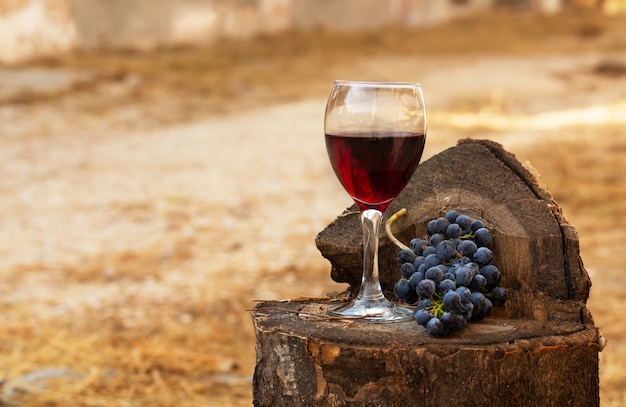 Copa de vino tinto y racimo de uvas sobre un fondo de madera vieja.