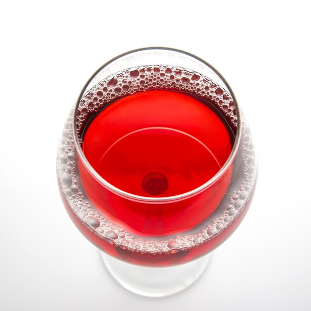 Foto copa con vino tinto sobre un fondo claro