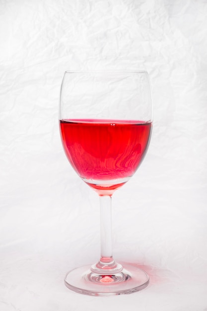Copa de vino tinto sobre un fondo de papel arrugado blanco.