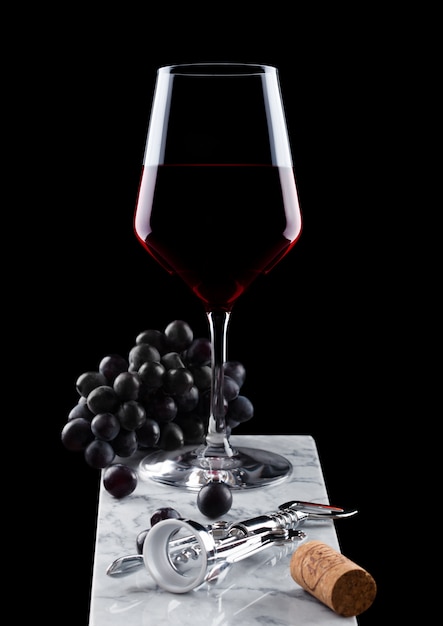 Copa de vino tinto con uvas sobre fondo negro