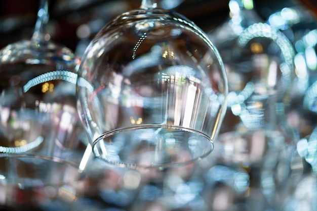 una copa de vino transparente cuelga en el estante del bar al fondo de otras copas de vino en el café. De cerca