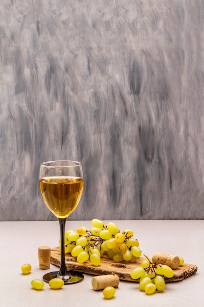 Copa de vino, uvas frescas y corchos en tabla de cortar de madera. Wine bar, bodega, concepto de cata de vinos.