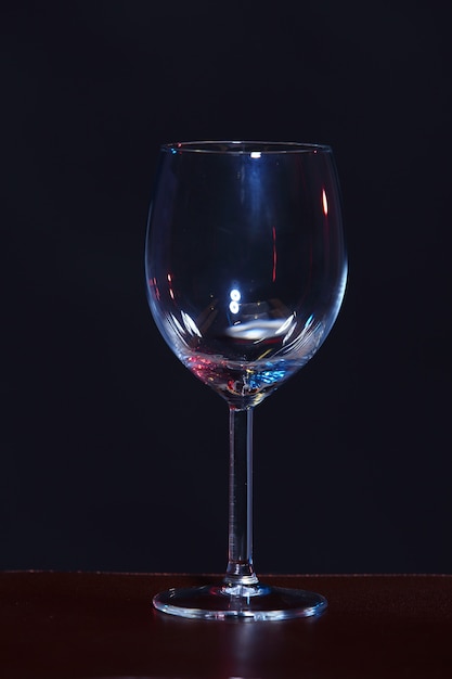 Copa de vino vacía en orden en la mesa sobre fondo negro, baja exposición