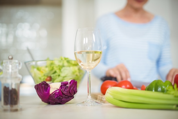 Copa de vino y verduras en encimera de cocina