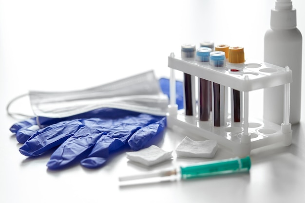 copas con análisis de sangre, jeringas, guantes y máscara
