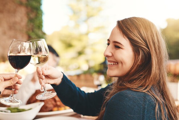 Foto copas de brindis con vino y cena de celebración con una mujer feliz por el evento festivo comida felicidad y almuerzo navideño de vítores femeninos con bebida alcohólica para celebrar la gratitud al aire libre