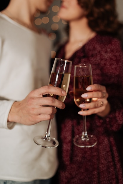Copas con champán de cerca en manos de una elegante pareja joven año nuevo