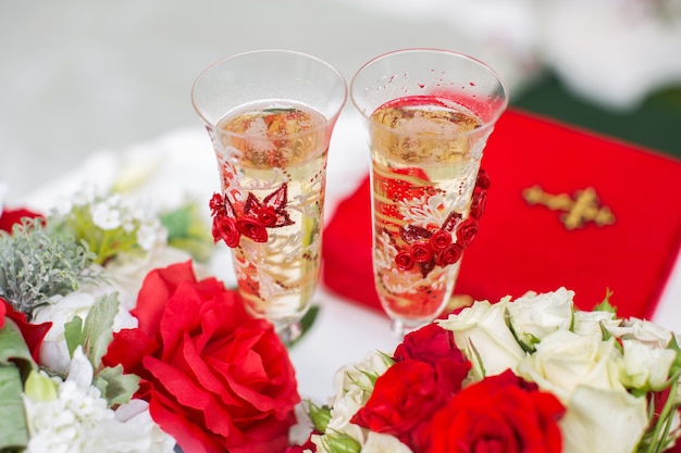 Las copas de champán. Ceremonia de boda al aire libre. Ramo de flores rojas.