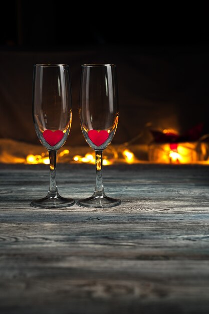 Copas de champán con corazones rojos sobre un fondo oscuro.