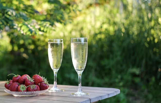 Copas de champán y fresas en una mesa en un jardín de verano