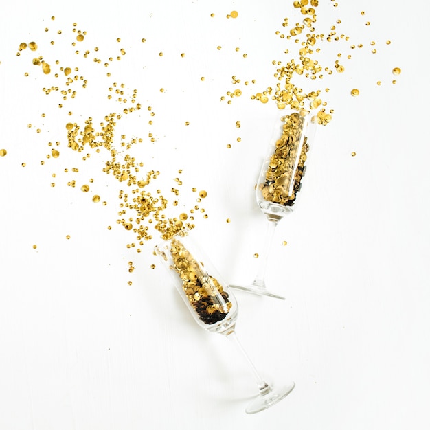 Copas de champán con oropel de confeti dorado sobre blanco