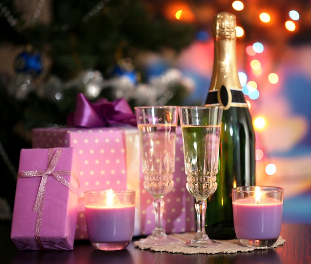 Copas de champán y regalos sobre fondo brillante