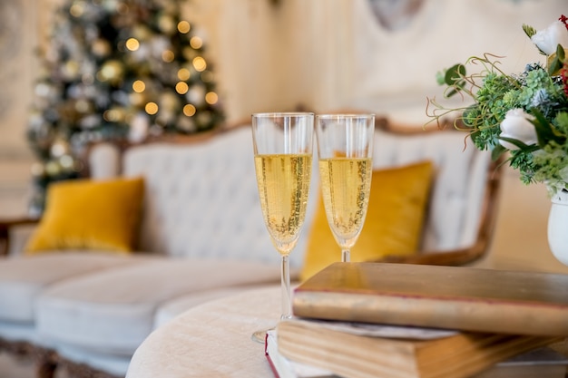 Copas de champán sobre árbol de Navidad parpadeante dorado