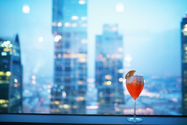 Copas de cóctel en el alféizar de la ventana por el cristal de un edificio alto