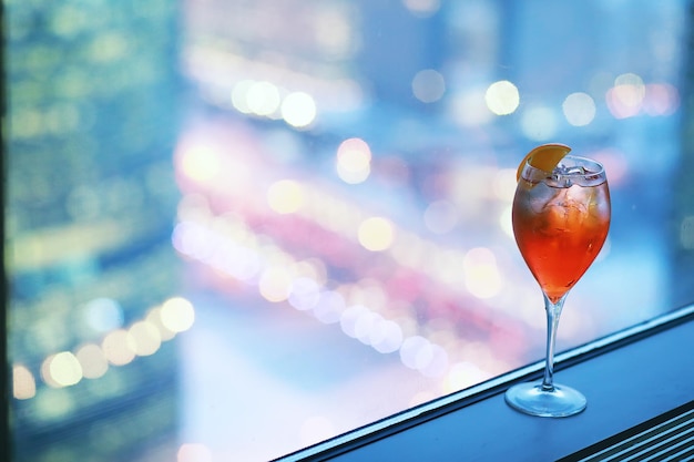 Copas de cóctel en el alféizar de la ventana por el cristal de un edificio alto