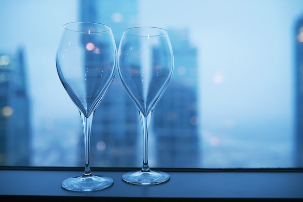 Copas de cóctel en el alféizar de la ventana por el cristal de un edificio alto