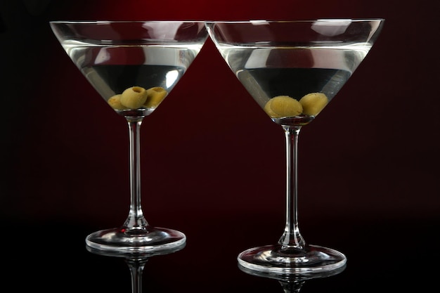 Copas de martini con aceitunas sobre fondo rojo oscuro