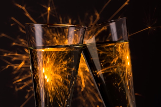 Copas tintinean con fondo de fuegos artificiales en la víspera de año nuevo