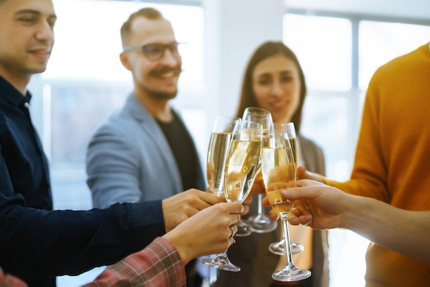 Copas tintineando con champán Compañeros de trabajo felices celebrando su logro empresarial