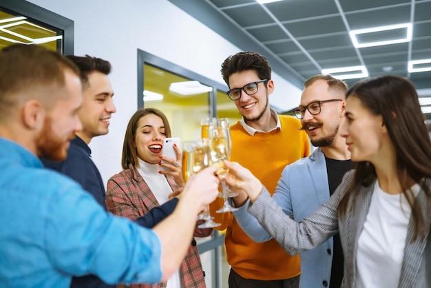 Copas tintineando con champán Compañeros de trabajo felices celebrando su logro empresarial