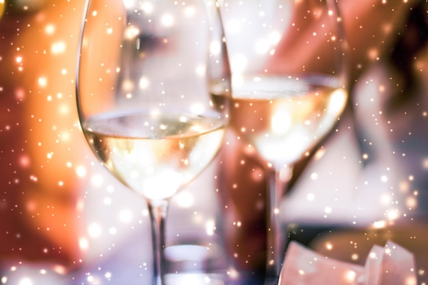 Copas de vacaciones de invierno de vino blanco y nieve brillante en el romance de Navidad de fondo