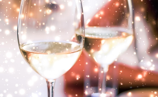 Copas de vacaciones de invierno de vino blanco y nieve brillante en el romance de Navidad de fondo