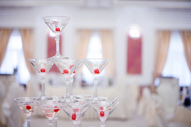 Foto copas de vidrio. pirámide de champagne. la colina sirve vino y cerezas. para el alcohol bebida festiva decoraciones del banquete. campo de profundidad pequeña