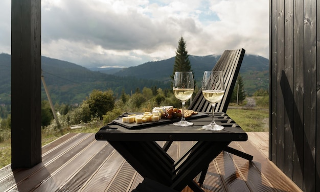 Copas de vino blanco y plato de queso en la terraza con vista a las montañas con espacio para copiar