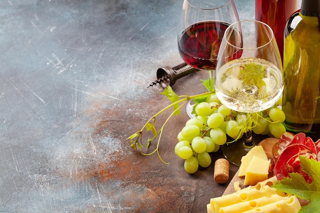 Copas de vino blanco y tinto uva y tabla de aperitivos