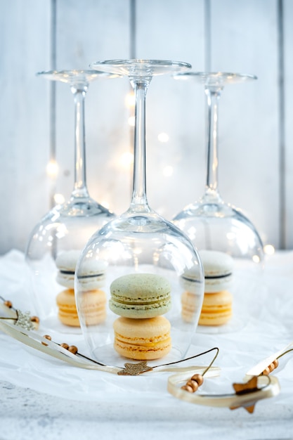 Copas de vino y galletas de macarrones pastel sobre fondo blanco.