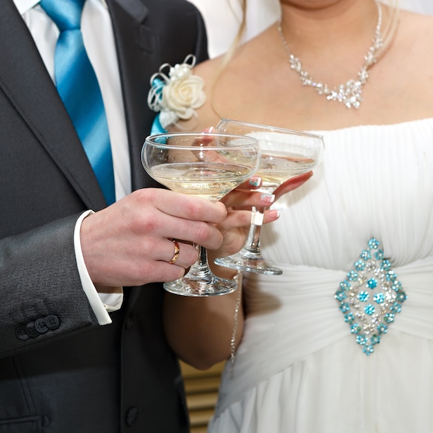 Copas de vino en manos de los novios en una fiesta de bodas.