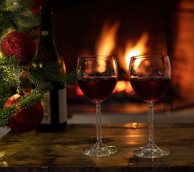 Copas de vino rojo quemando la chimenea de fondo decoración del árbol de Navidad