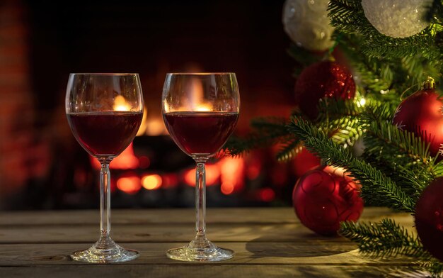 Copas de vino rojo quemando la chimenea de fondo decoración del árbol de Navidad