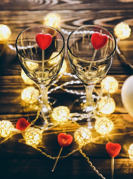 Copas de vino románticas con corazones para el día de San Valentín Fecha y cena Luces acogedoras Fondo de madera Postal de vacaciones Concepto de amor