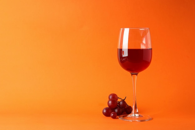 Copas de vino tinto y uva sobre fondo naranja