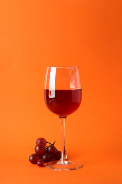 Copas de vino tinto y uva sobre fondo naranja