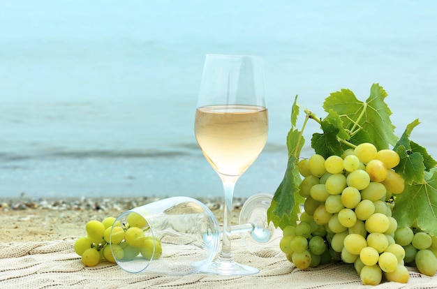 Copas de vino y uvas frescas en la playa