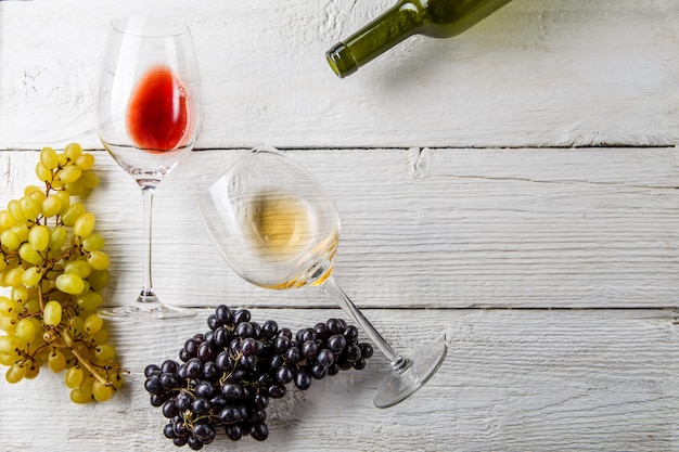 copas de vino, uvas negras y verdes, botella en mesa de madera blanca, espacio vacío para texto