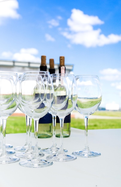Copas de vino vacías sobre un mantel blanco contra un cielo azul Preparación para un banquete o buffet Foto vertical