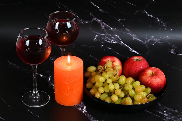 Copas con vino, velas, manzanas y uvas.