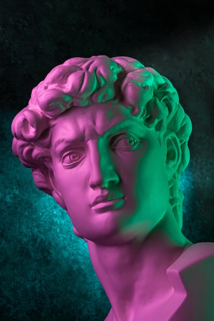 Copia de yeso de la estatua de la cabeza david en colores de neón brillantes para artistas en un rostro de fondo oscuro famoso