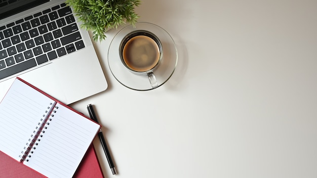 Copie a mesa de escritório com laptop, caderno e caneta com café. Tabela de vista superior.